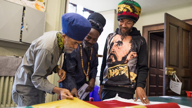 Rastafarians Iman, Lawi and Iqulah stand together and view collections items gifted by Haile Selassie